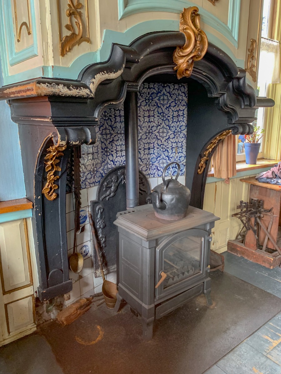 Placa de hierro fundido holandesa antigua detrás de una estufa en una antigua chimenea holandesa