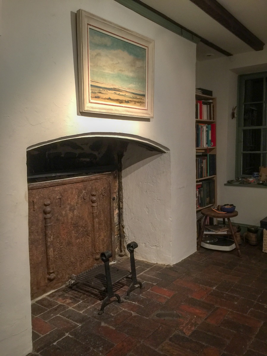 Una chimenea colonial no utilizada en el área de Nueva York con una robusta placa de hierro fundido francesa