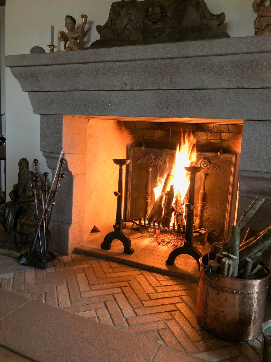 Una sólida chimenea polaca con una robusta placa de hierro fundido francesa antigua y tenazas