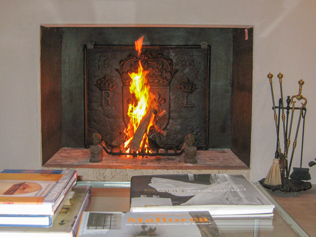 Una chimenea moderna española con una placa de hierro fundido francesa del siglo XVII y tenazas del siglo XIX